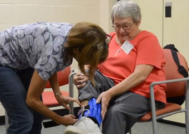 woman helping older woman to put on exercise weight
